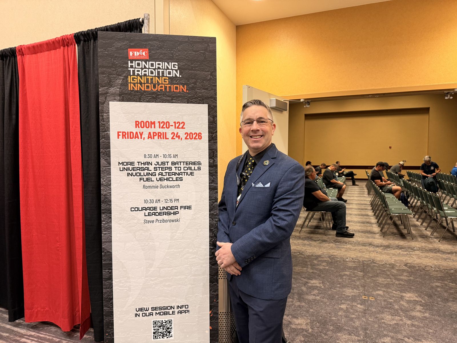 Rom Duckworth beside the session sign for More Than Just Batteries at FDIC International 2026.