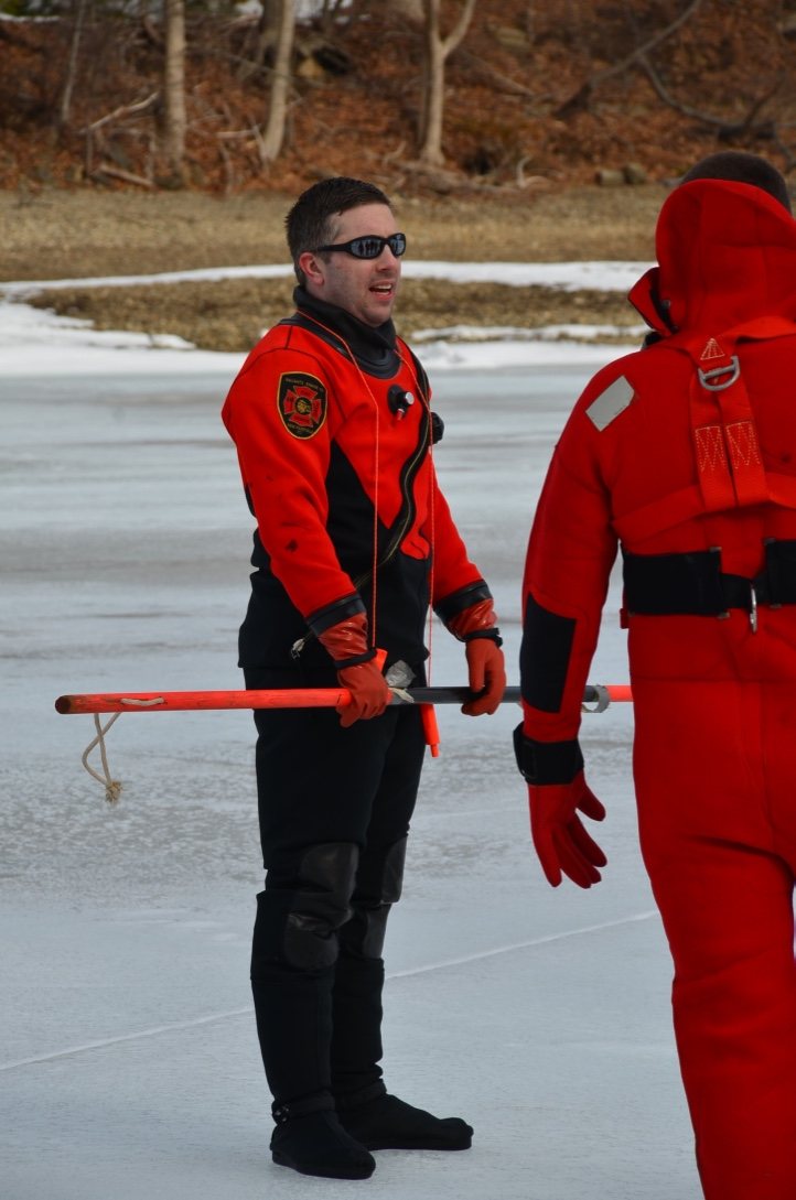 Rom Duckworth in a dry suit holding a reach pole during ice rescue instruction.