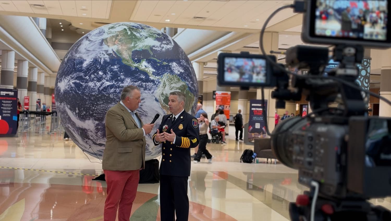 Rom Duckworth giving an on-camera interview in a conference exhibit hall.
