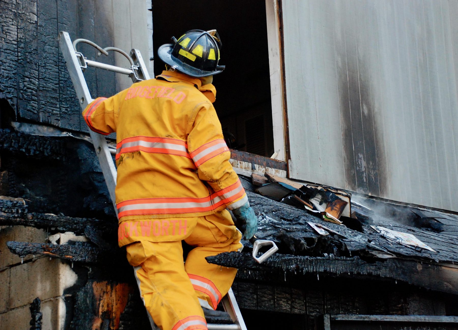 Rom Duckworth climbing a ground ladder at a working structure fire.
